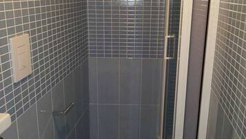 Ein Badezimmer mit Toilette, Dusche und Glastür.