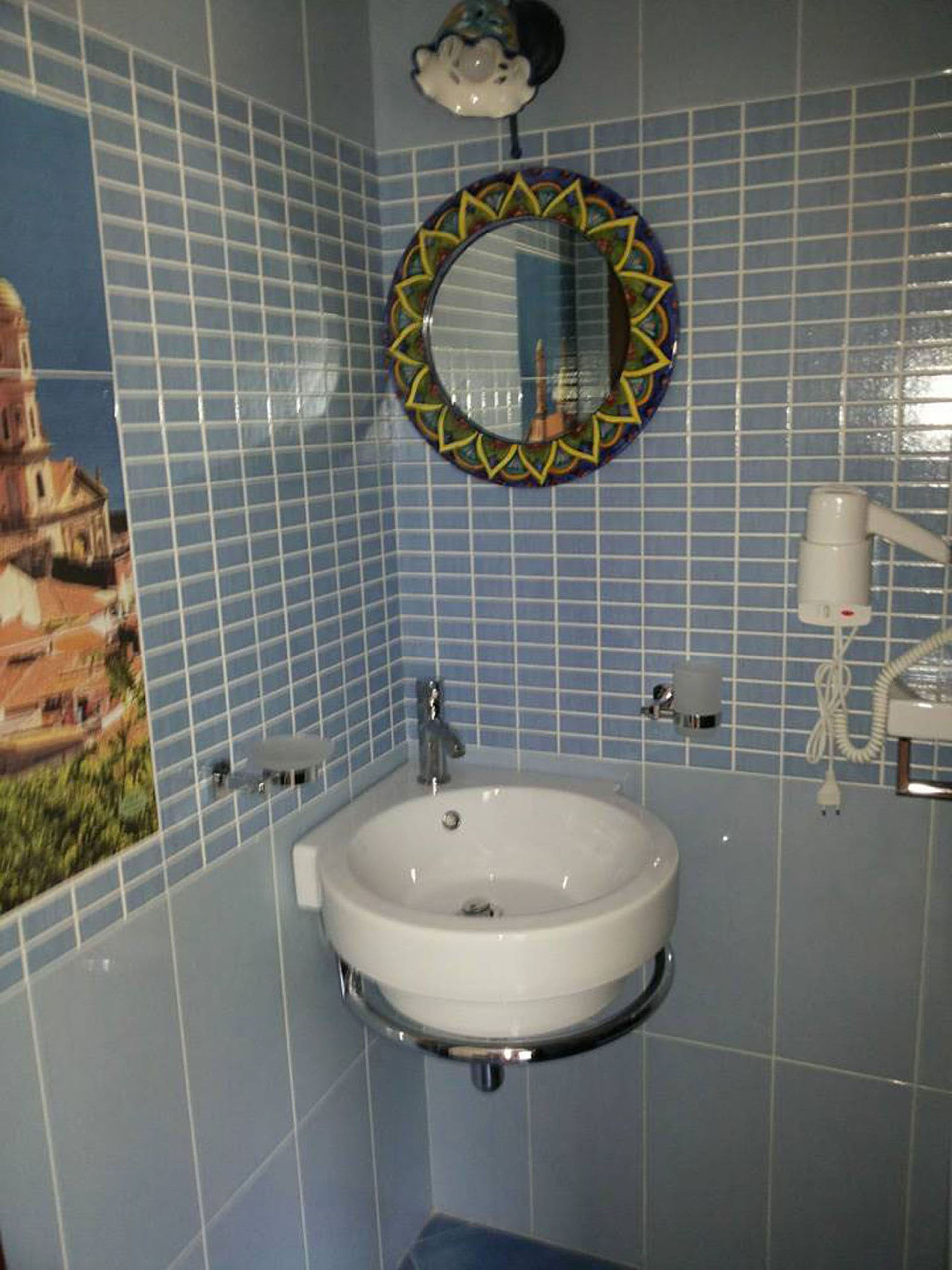 Une salle de bain avec un lavabo, un miroir et un motif décoratif en carreaux sur les murs.