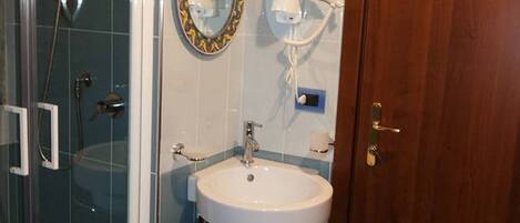 Un baño con cabina de ducha de vidrio, lavabo con espejo y puerta de madera.
