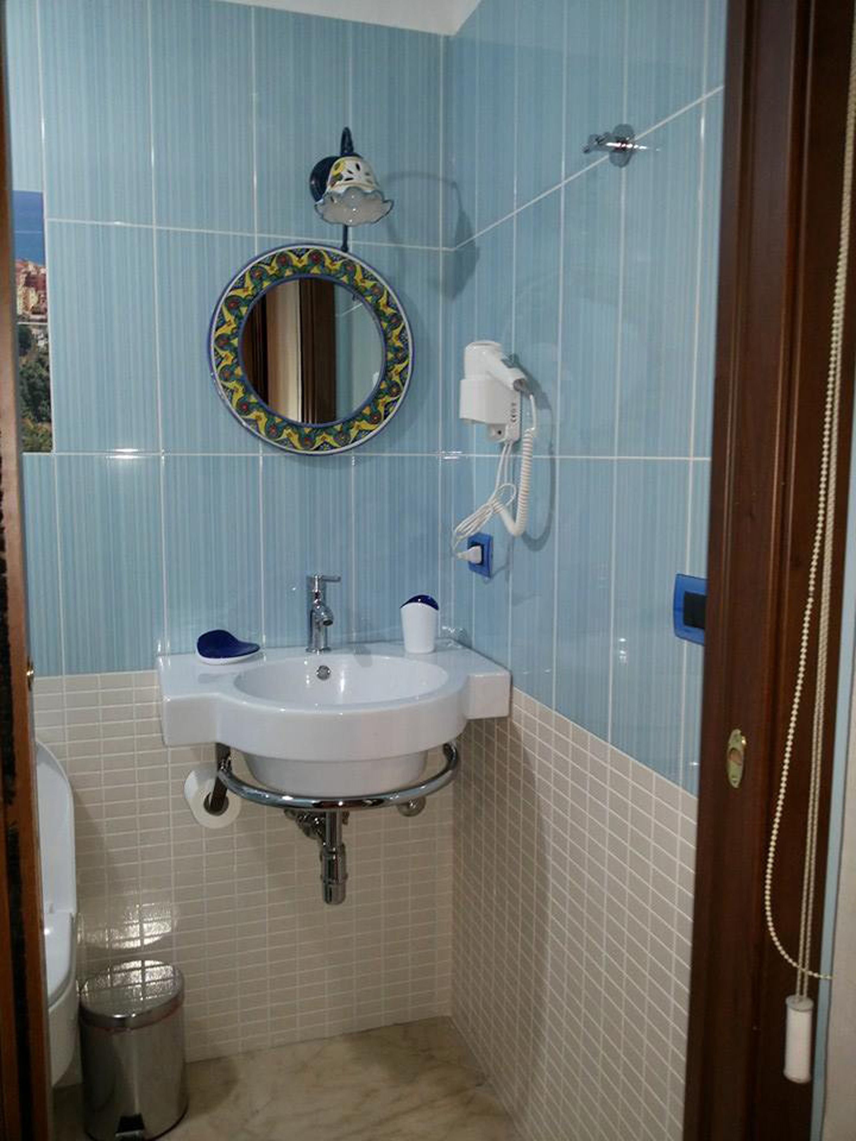 A bathroom with a sink, mirror, and a hairdryer on the wall.