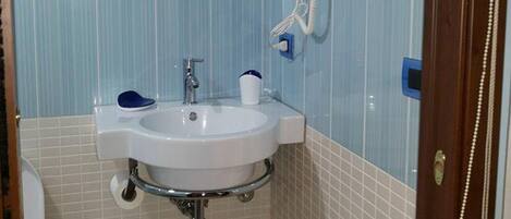 A bathroom with a sink, mirror, and a hairdryer on the wall.