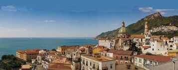 Un pueblo costero con edificios históricos, una iglesia destacada con cúpula y una montaña al fondo.