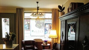 Ein Hotelzimmer mit einem großen Spiegel, zwei Ledersesseln, einem kleinen Tisch mit einer Lampe und Blick auf die Straße.