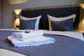 A neatly made bed with a folded white towel and two pillows.