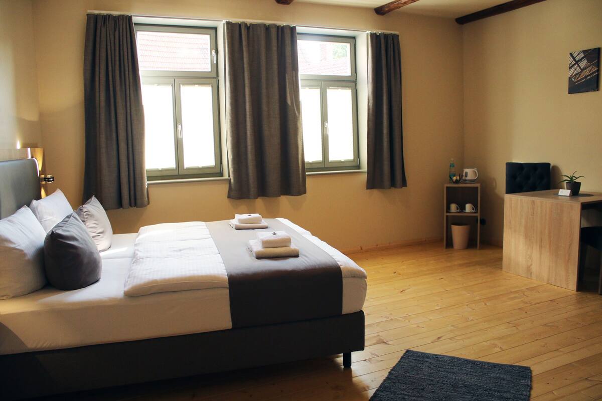 Un dormitorio con cama, escritorio y ventana con cortinas.