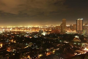 A nighttime cityscape with illuminated buildings and a bridge. - BSA Mansion (Makati)