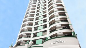 A tall, multi-story building with a curved facade, labeled "BSA MANSION." - BSA Mansion (Makati)