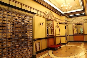 A lobby with a large safe, a chandelier, and a red cart. - BSA Mansion (Makati)