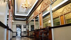 A lobby with a chandelier, ornate wall designs, and a seating area with tables and chairs. - BSA Mansion (Makati)