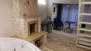 A bathroom with a stone fireplace, a bathtub, and a dining area with a table and chairs. - Alesta Butik Otel (Sile)