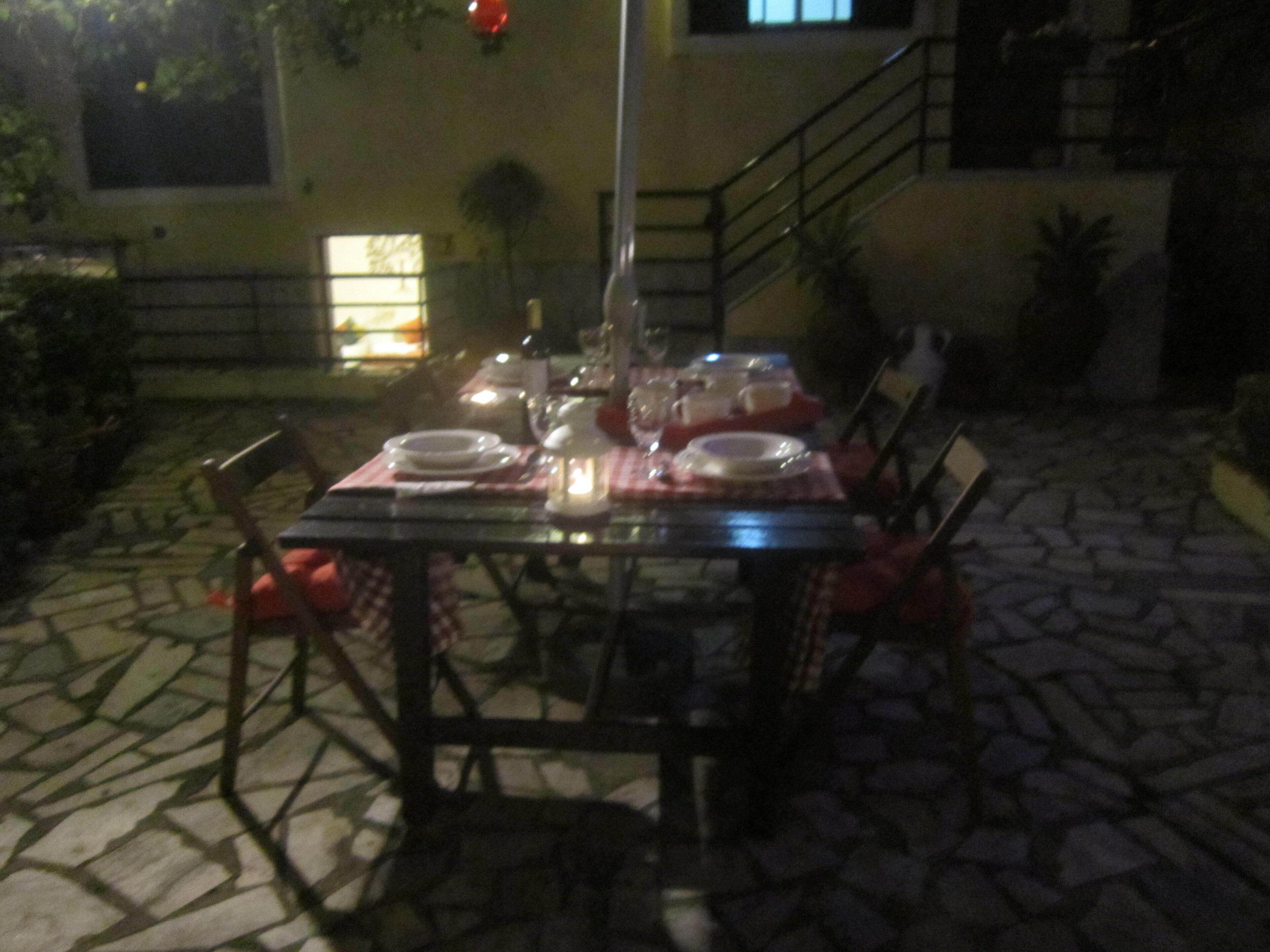 An outdoor dining area with a table set for four, surrounded by chairs.
