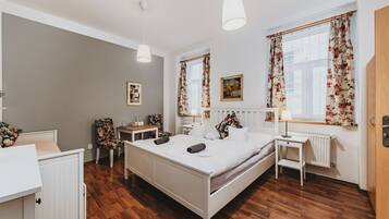 Une chambre avec un lit blanc, un plancher en bois, un bureau et une chaise.