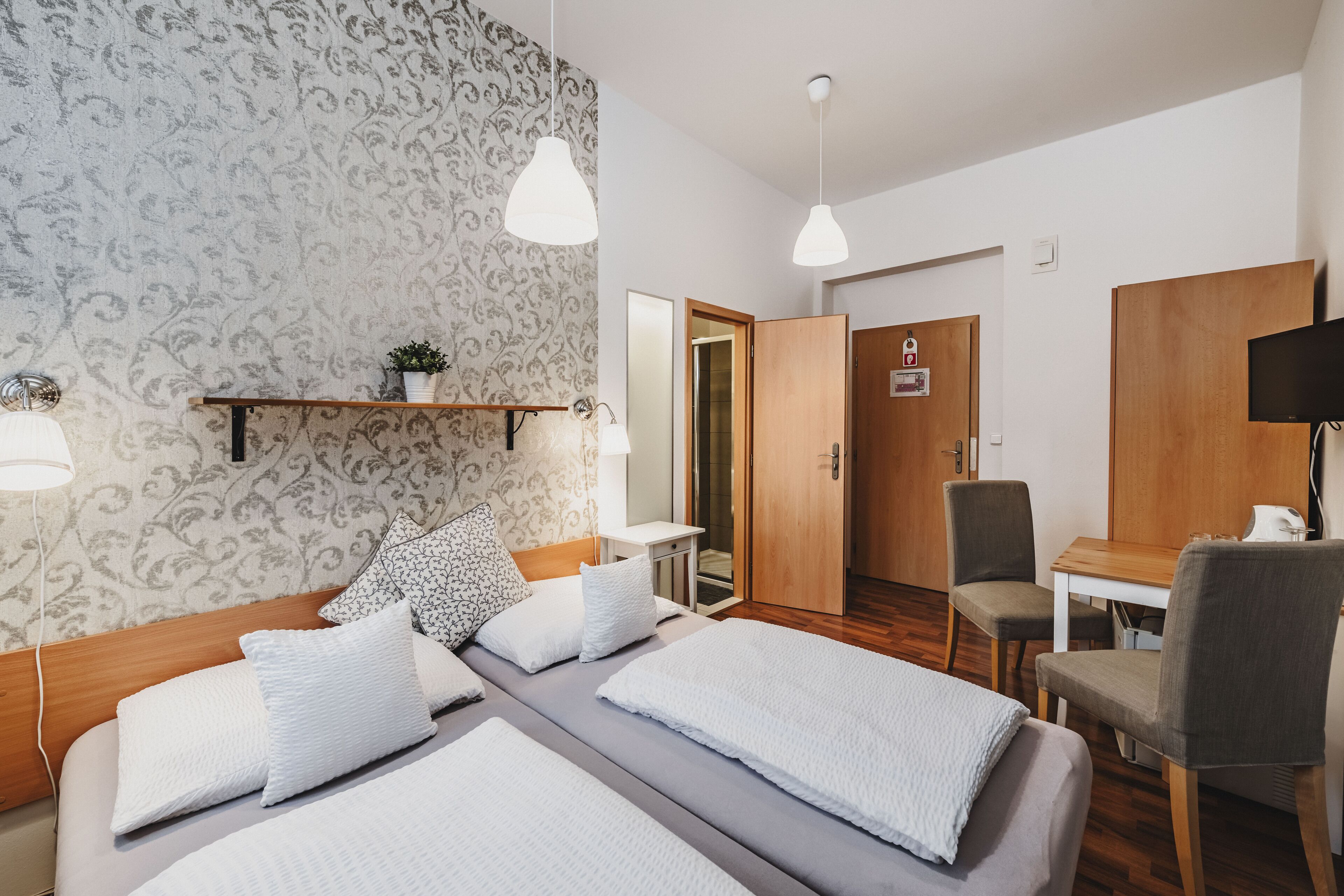 Ein Hotelzimmer mit Bett, Nachttischen, Schreibtisch, Stuhl, Spiegel und Kleiderschrank.