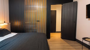 A modern hotel room with a bed, a bedside table, a wall-mounted TV, and a sliding door leading to another room. - Doma Zagreb (Zagreb)