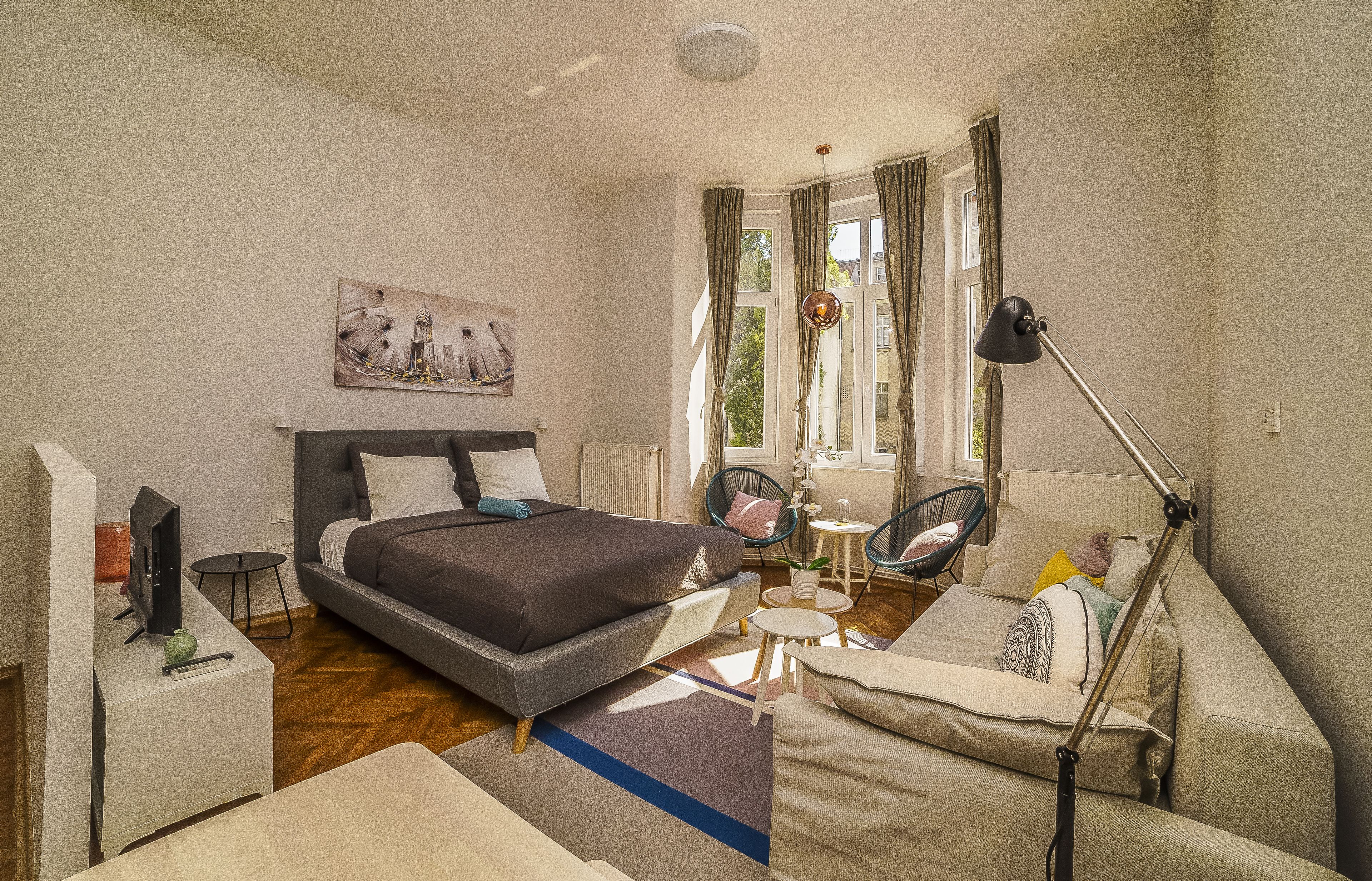 Un dormitorio moderno con cama, mesita de noche, lámpara y vistas al exterior.