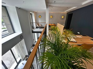 Un espacio de oficina moderno con una mesa larga, varias sillas y un balcón con barandilla.