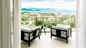 A balcony with two white sofas and a small table, overlooking a coastal town and mountains. - OCEAN Apartment 2 Bedroom -SABINA DaNang (Da Nang)