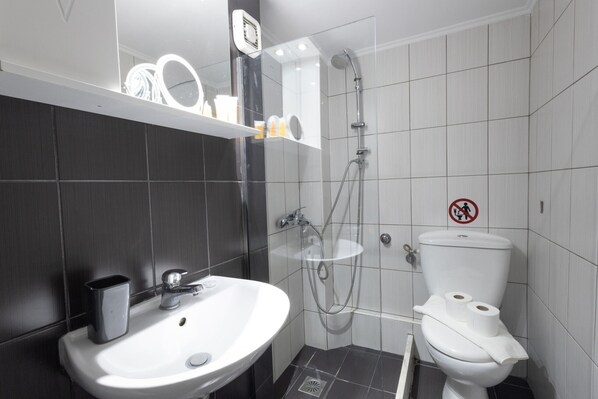 A modern bathroom with a white sink, a toilet, and a shower.