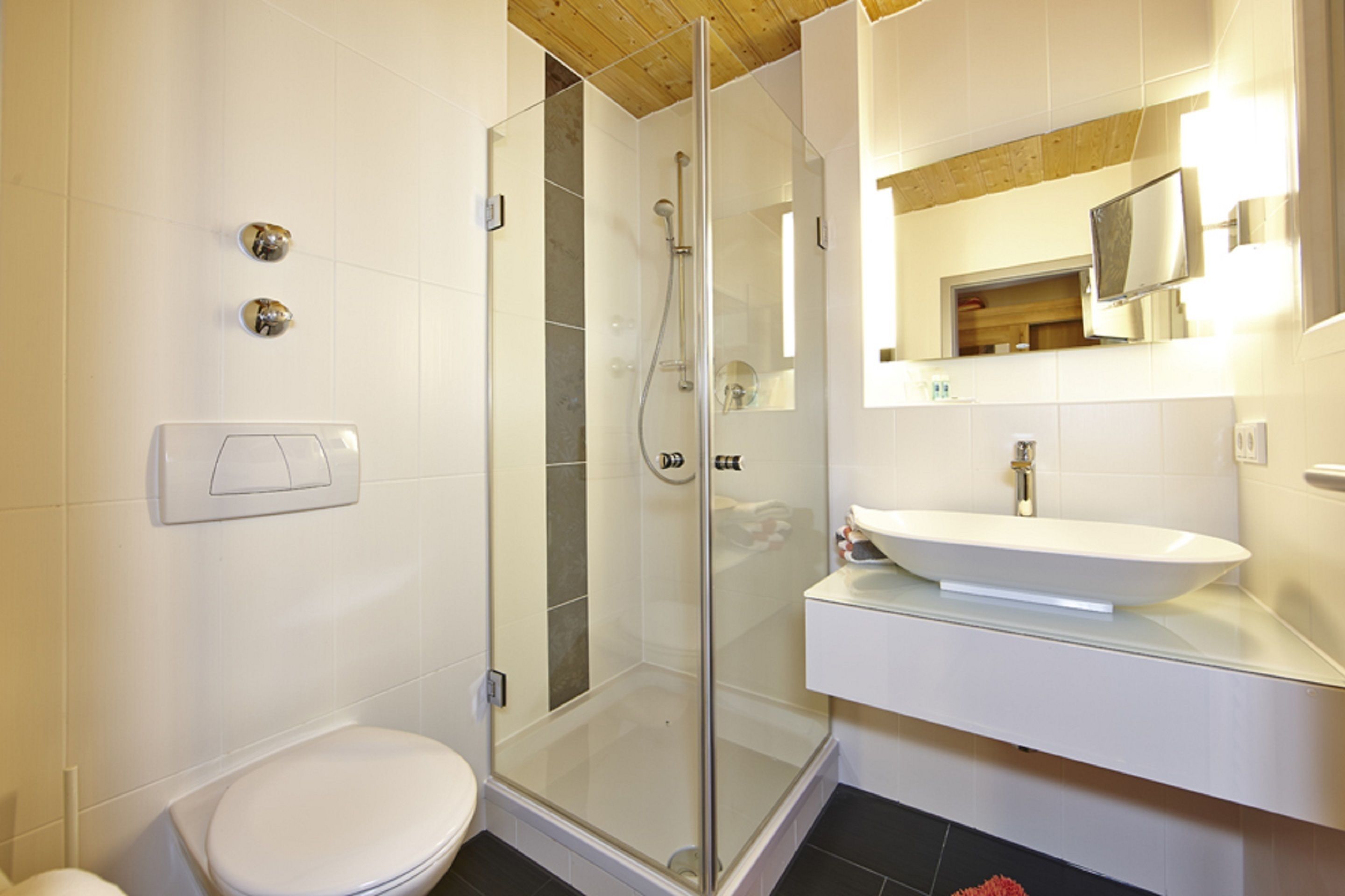 A modern bathroom with a glass-enclosed shower, a white sink, and a toilet.