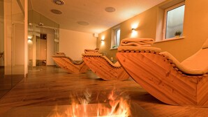 Una habitación con suelo de madera, una chimenea y sillas de madera.