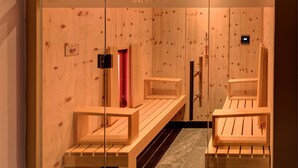 Un cuarto de sauna con bancos de madera y una puerta de vidrio.