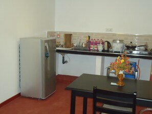 Eine kleine Küche mit Kühlschrank, Spüle und einem Esstisch mit Stuhl.