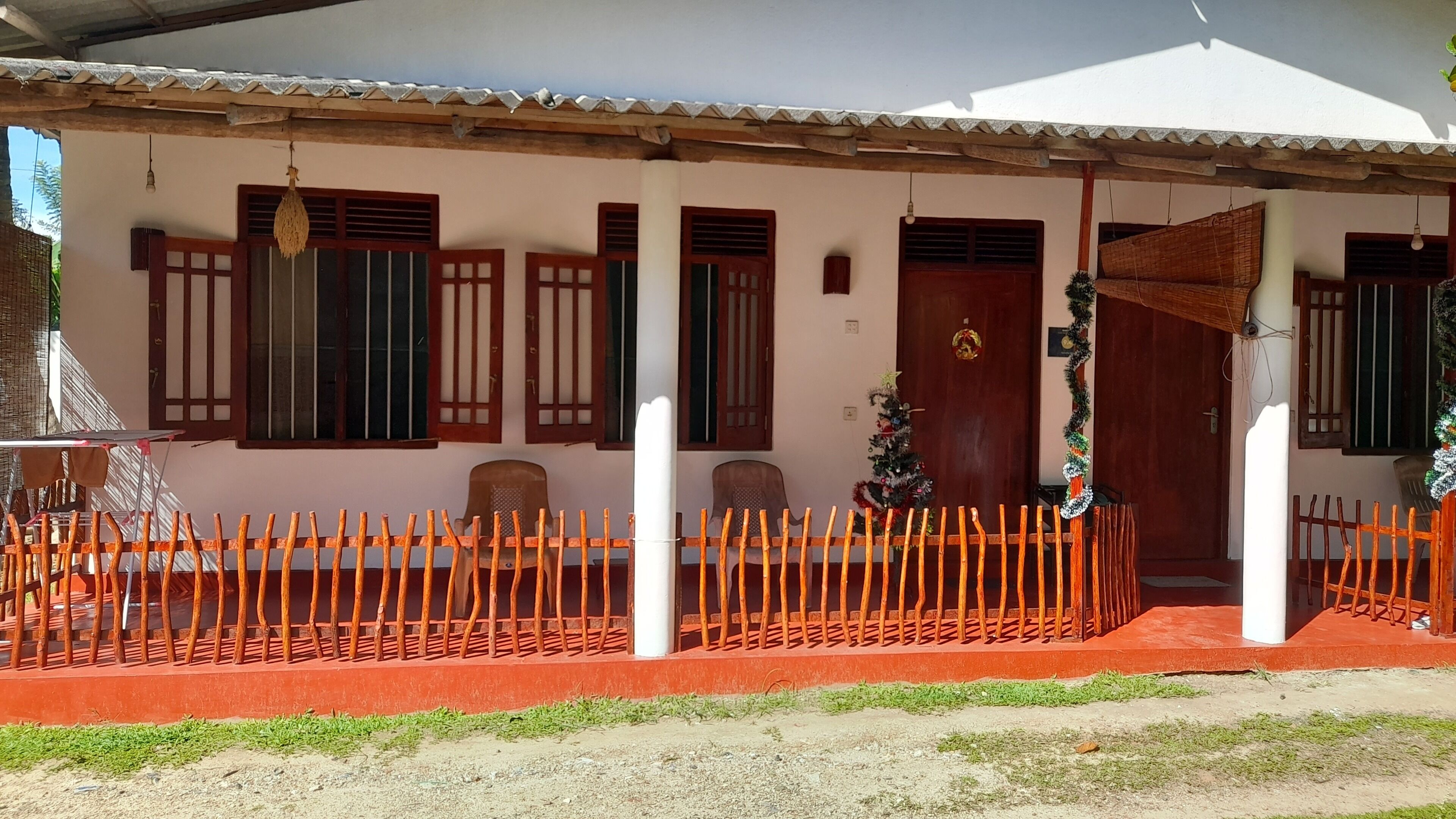 A house with a porch, a red fence, and a Christmas tree.