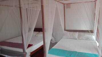 A room with two single beds, each with a mosquito net.