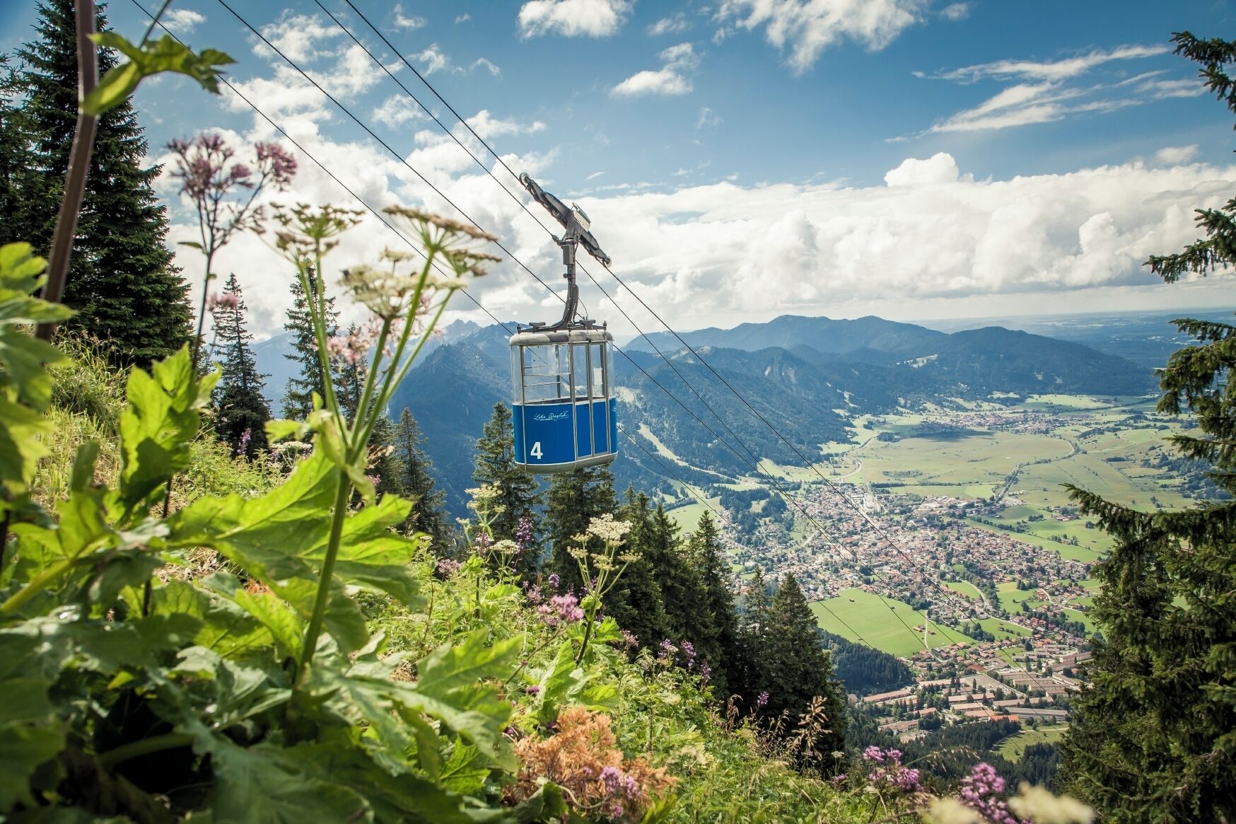 Un teleférico con el número 4, rodeado de vegetación y montañas al fondo.