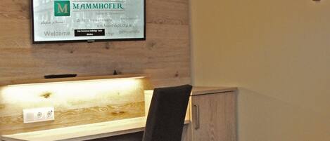 A modern room with a wooden desk, a chair, and a cabinet. A framed welcome sign is on the wall.