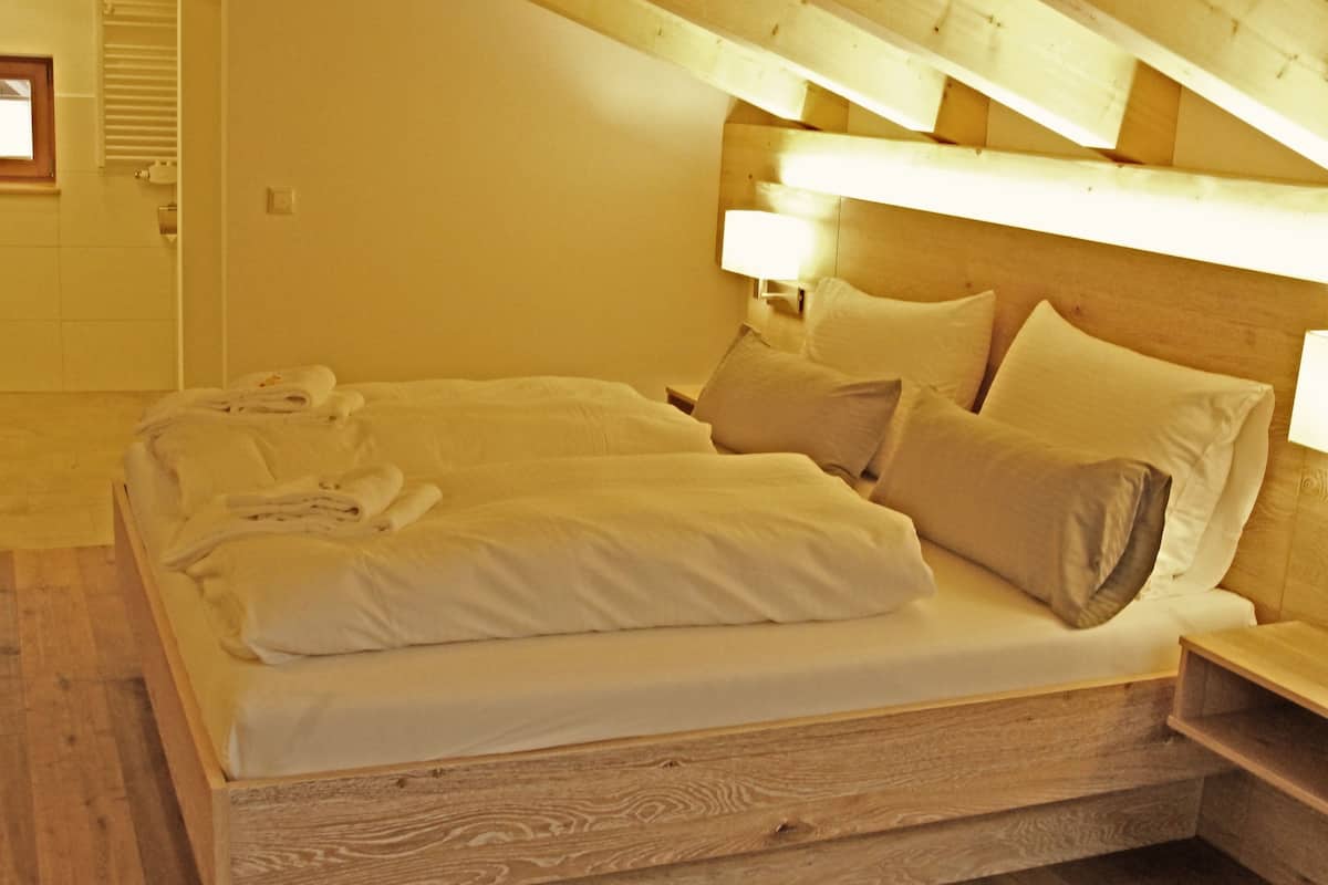 A wooden bed in a room with a sloped ceiling.