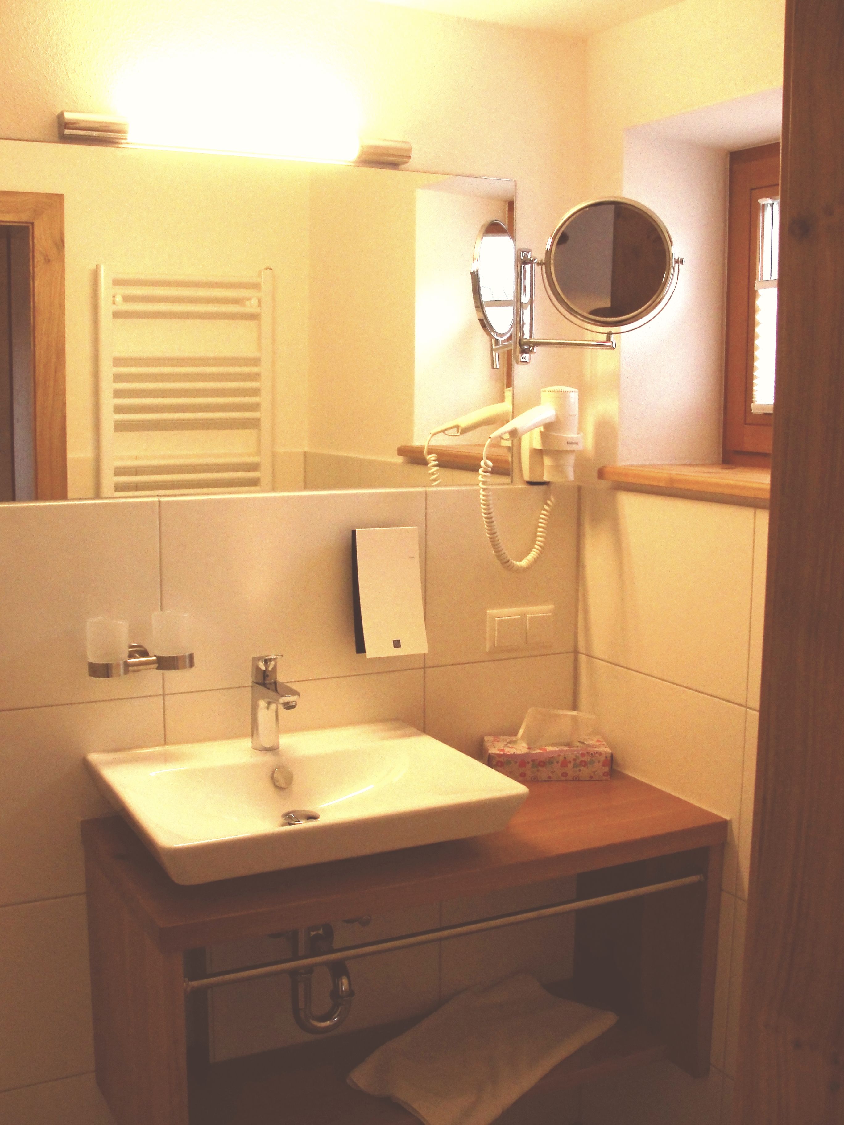 Une salle de bain avec un lavabo, un miroir, un porte-serviettes et une petite fenêtre.