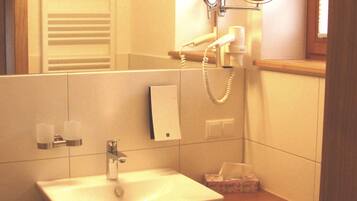 Une salle de bain avec un lavabo, un miroir, un porte-serviettes et une petite fenêtre.