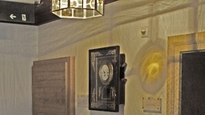 A room with a wooden door, a black chair, a wall-mounted clock, and a light fixture. - Mammhofer Suite & Breakfast (Oberammergau)