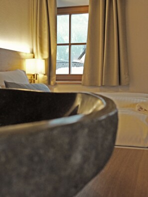 A hotel room with a bed, a bedside table with a lamp, and a window with curtains. - Mammhofer Suite & Breakfast (Oberammergau)