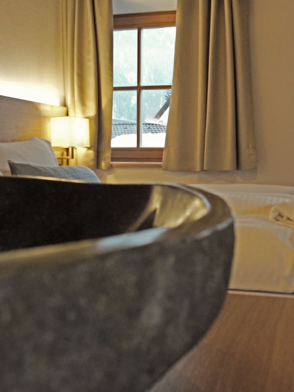 Una habitación de hotel con una cama, una mesita de noche con lámpara y una ventana con cortinas.
