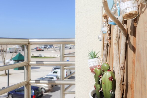 A balcony with a view of a parking lot and a building across the street.