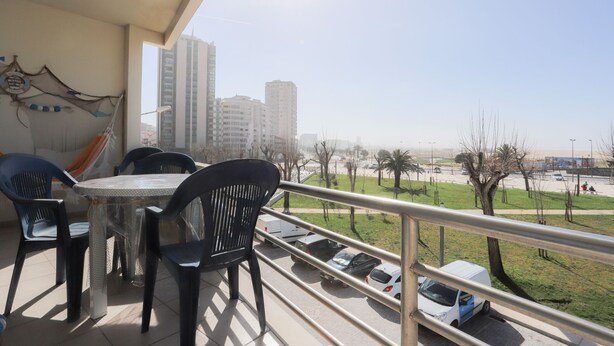 Ein Balkon mit Tisch und Stühlen, mit Blick auf einen Parkplatz und Gebäude.