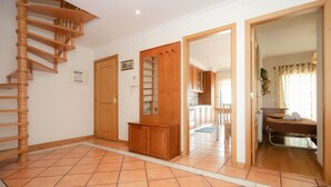 Ein geräumiger Flur mit einer Holztreppe, einem Holzschrank und einer Tür zu einem Schlafzimmer mit Bett und Heizkörper.