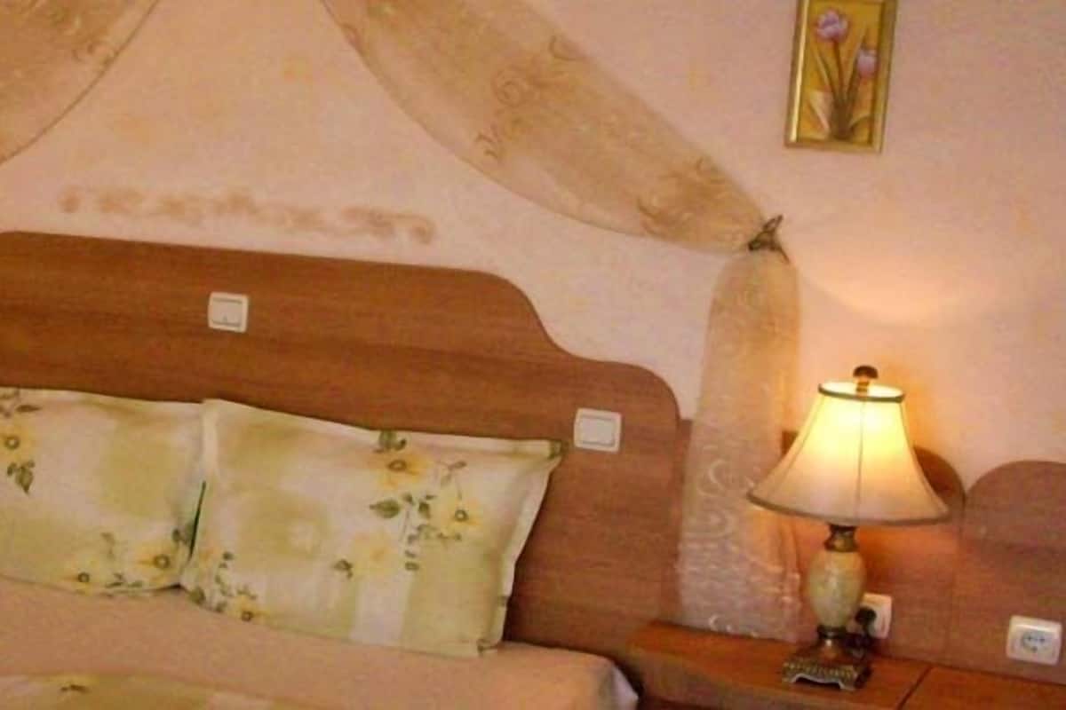 A bed with a wooden headboard, two bedside lamps, and floral-patterned pillows.