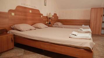 A bedroom with a large bed, a smaller bed, a nightstand, a lamp, and a wardrobe.