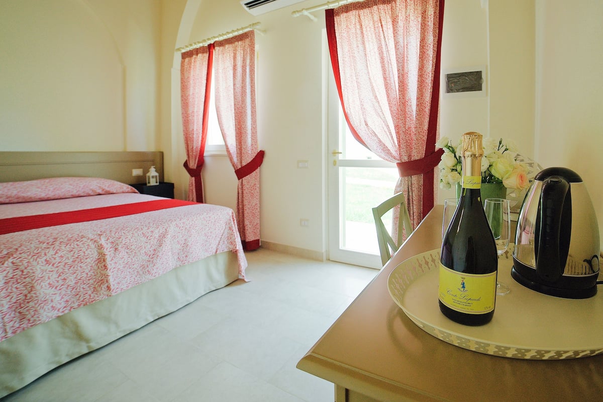 Een hotelkamer met een bed, een tafel met champagne en gordijnen.