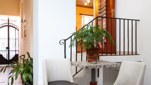 A staircase with a wooden railing, a potted plant, and two chairs with black cushions.
