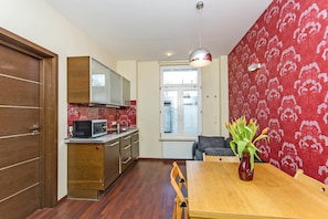 A compact kitchen with a microwave, wooden cabinets, and a dining table with chairs.