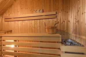 Un sauna en bois, avec des bancs, un seau et un appareil de chauffage.