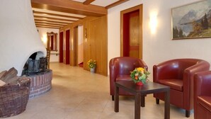A hotel lobby with a fireplace, leather chairs, a table with flowers, and a painting on the wall.