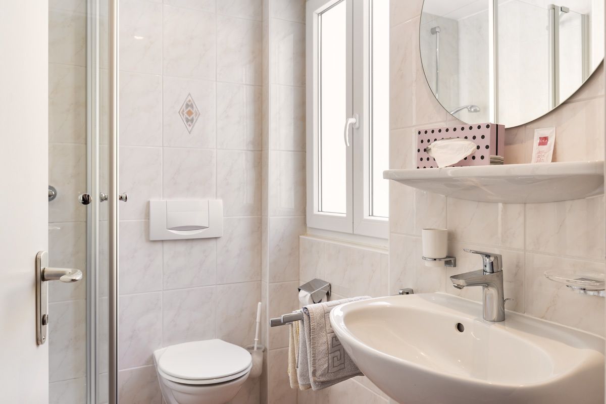 A modern bathroom with a glass shower enclosure, a white toilet, a sink with a mirror above it, and a towel rack.