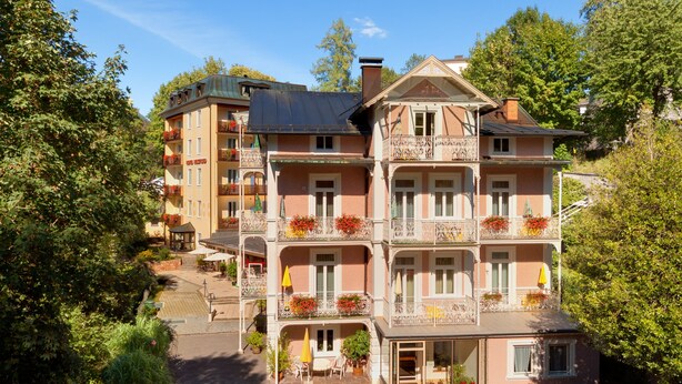 A multi-story hotel with balconies, outdoor seating, and a central courtyard.