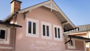 A pink building with the sign "HOTEL GARNI Bergfried & Schönblick".
