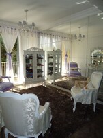 A room with white furniture, including chairs and a cabinet with glass doors.